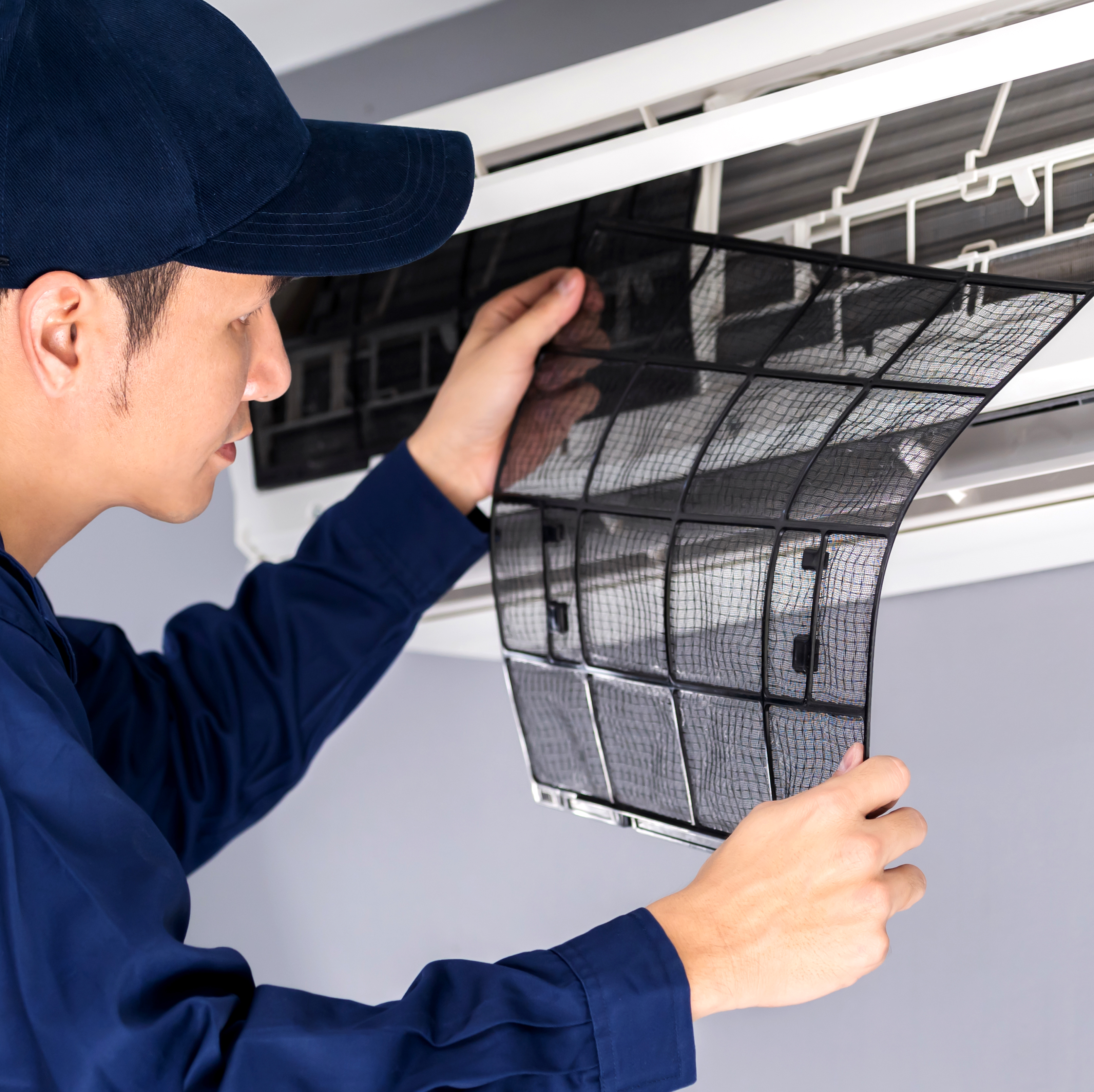 Photo of a man removing the cover on an air conditioning unit